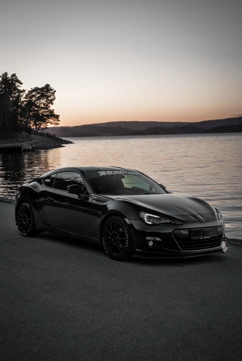 Coupé negro frente al mar al atardecer